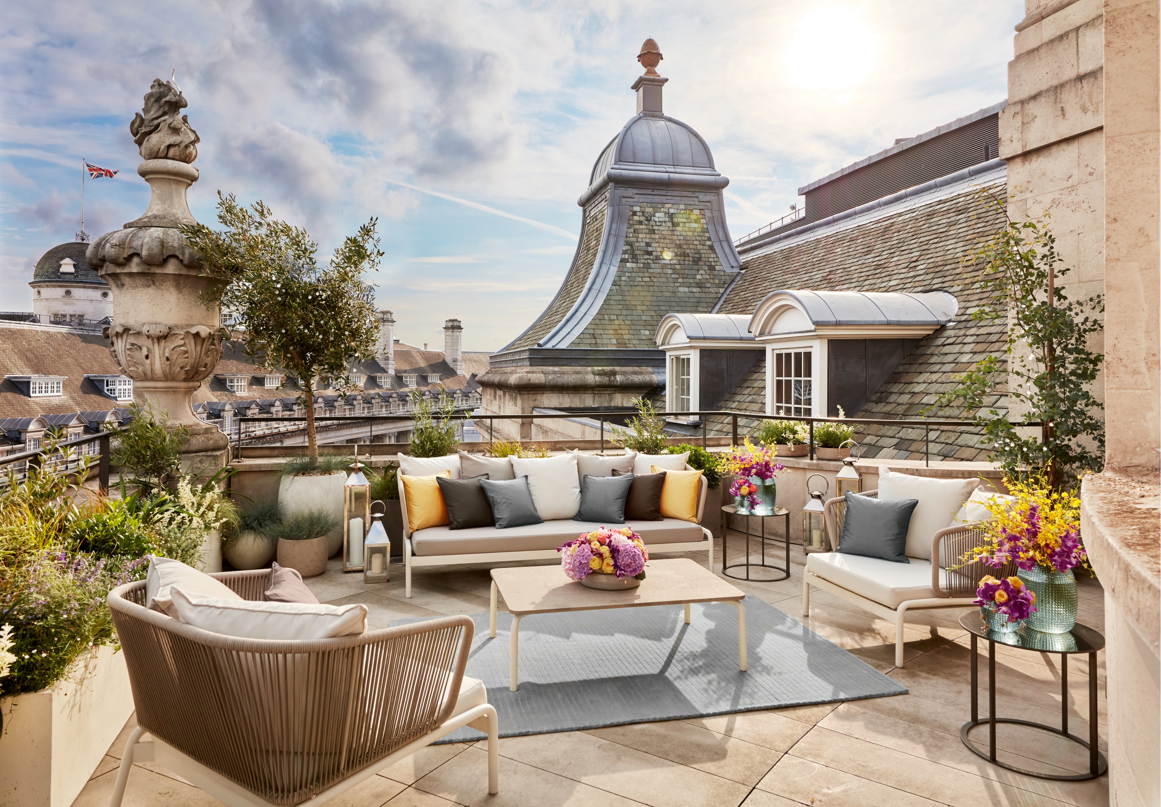 A rooftop terrace with foliage and lounge seating overlooking buildings