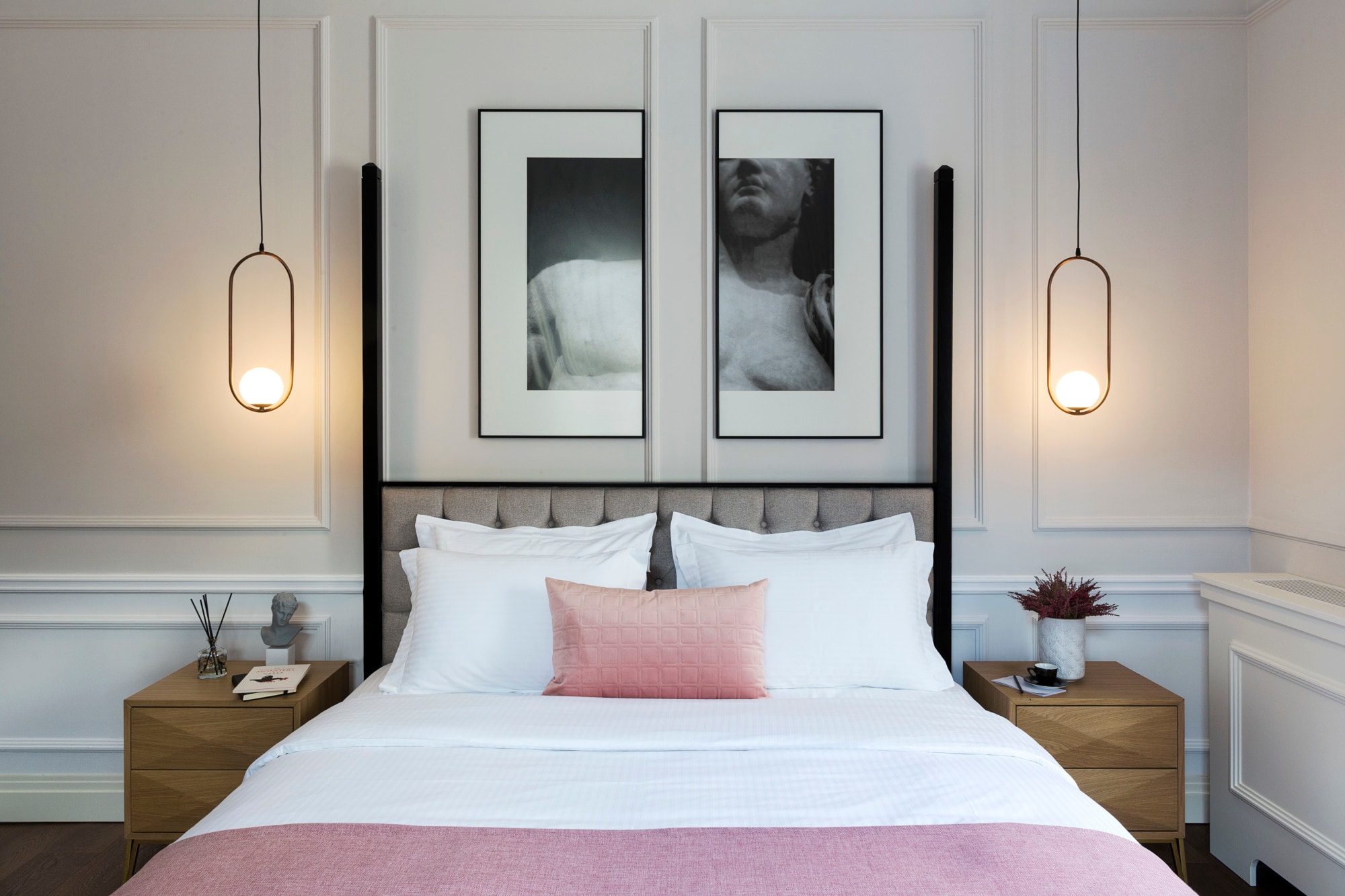 a hotel room with a large bed with pink blankets, and a modern black-and-white photo hanging above the gray headboard