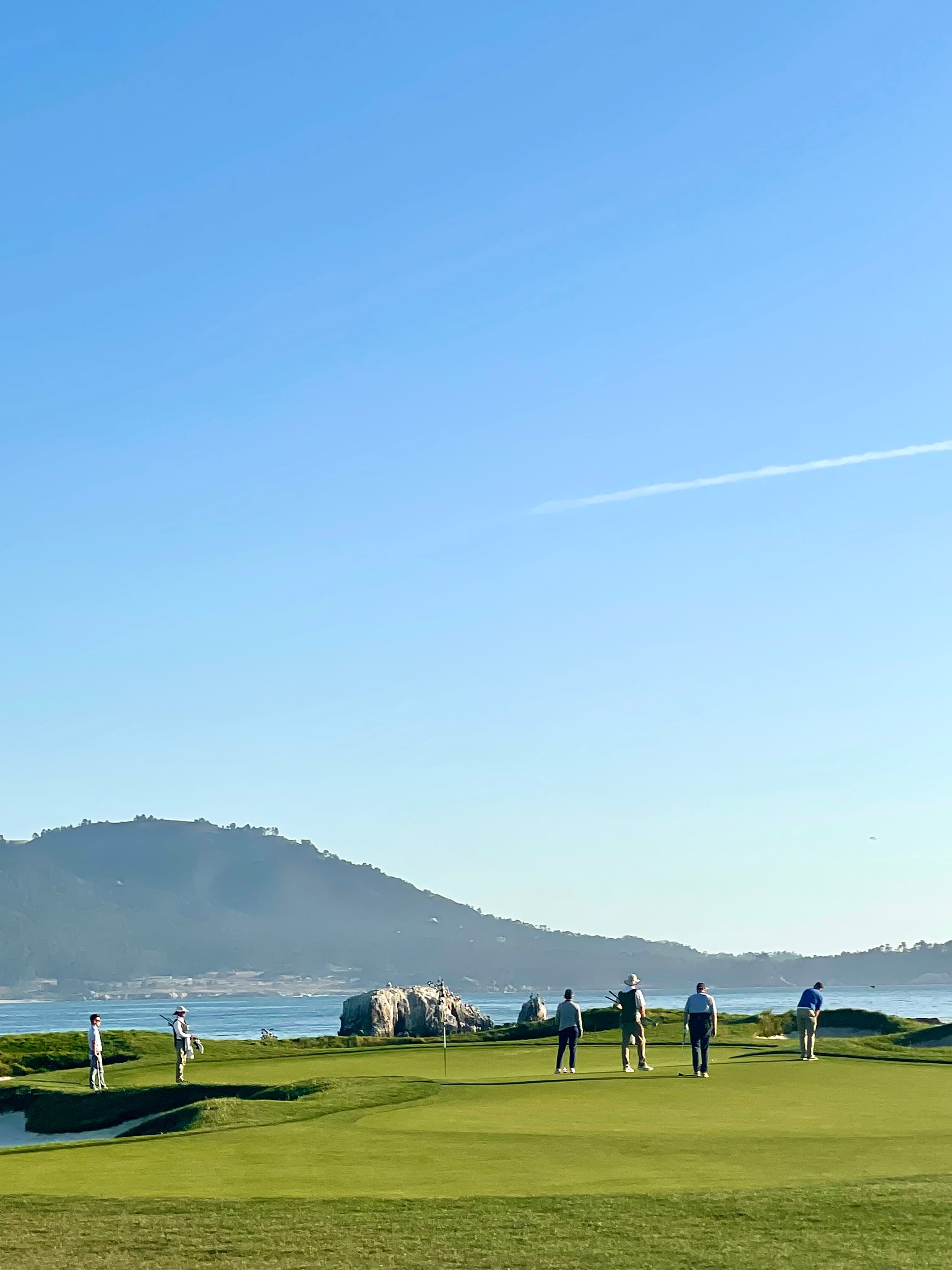 A picture of Kiki golfing on an open golf course with blue skies.