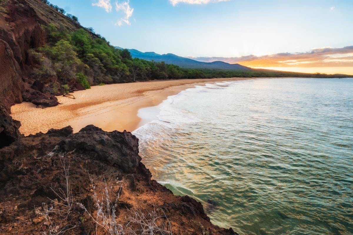 Tropical beach with turquoise waters and sandy shore in Maui right before sunset.