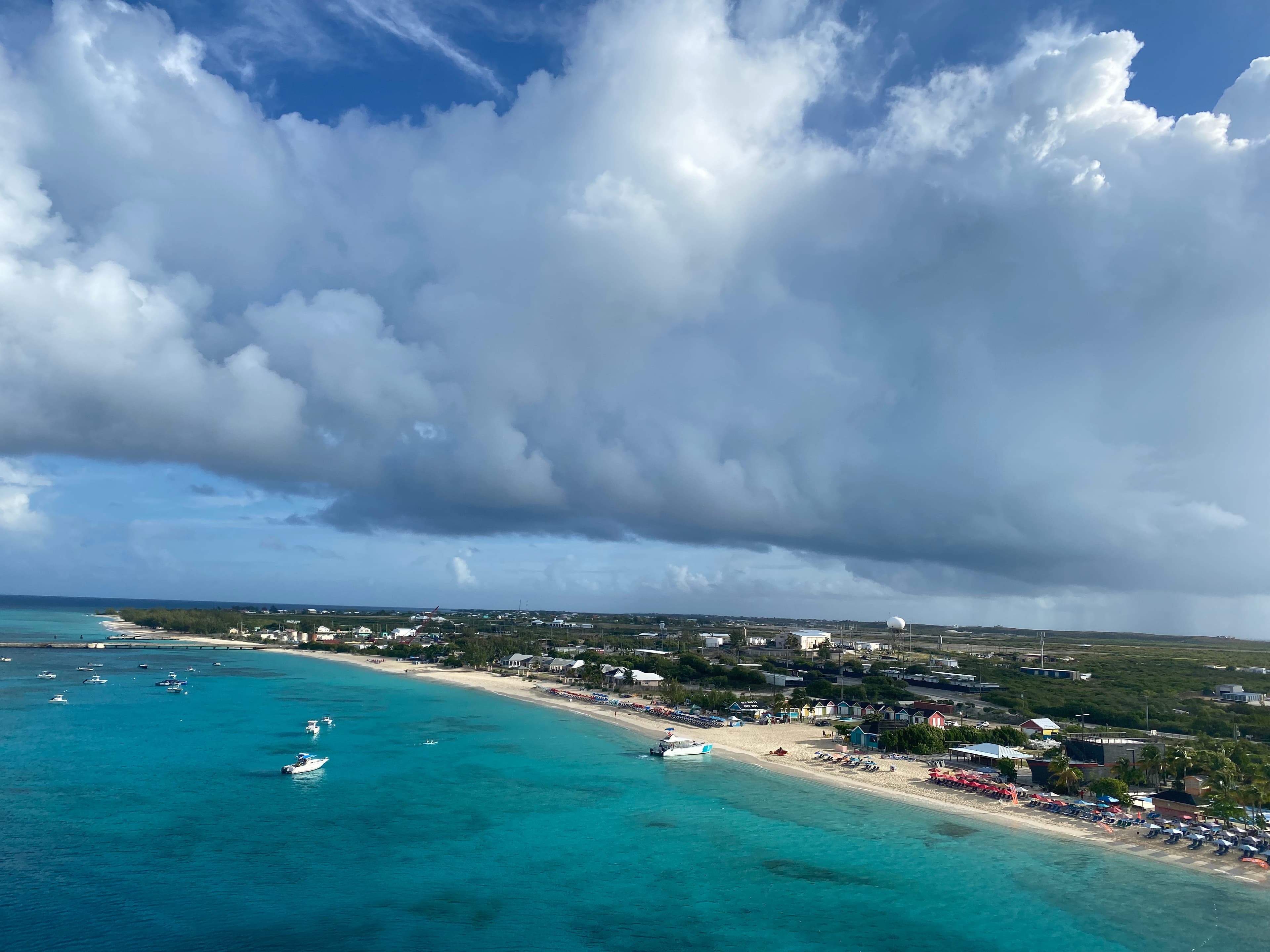 An aerial view of boats scattered on turquoise blue water and a coastal town