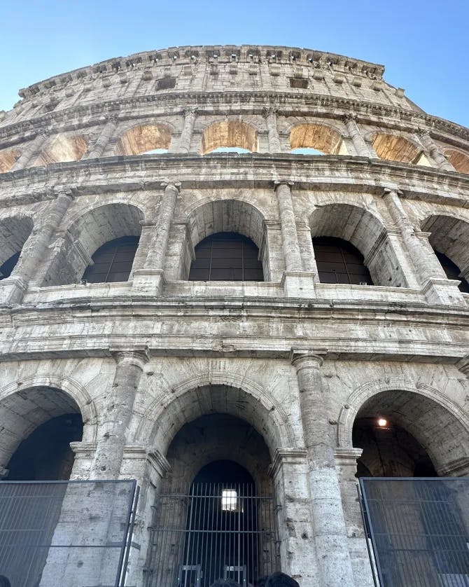 Picture of Colosseum with a clear blue sky and multiple levels of a historic sight. 
