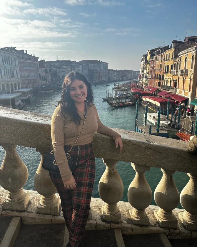 Picture of Brittany standing on stairs in Venice with the canal and yellow buildings in the background 