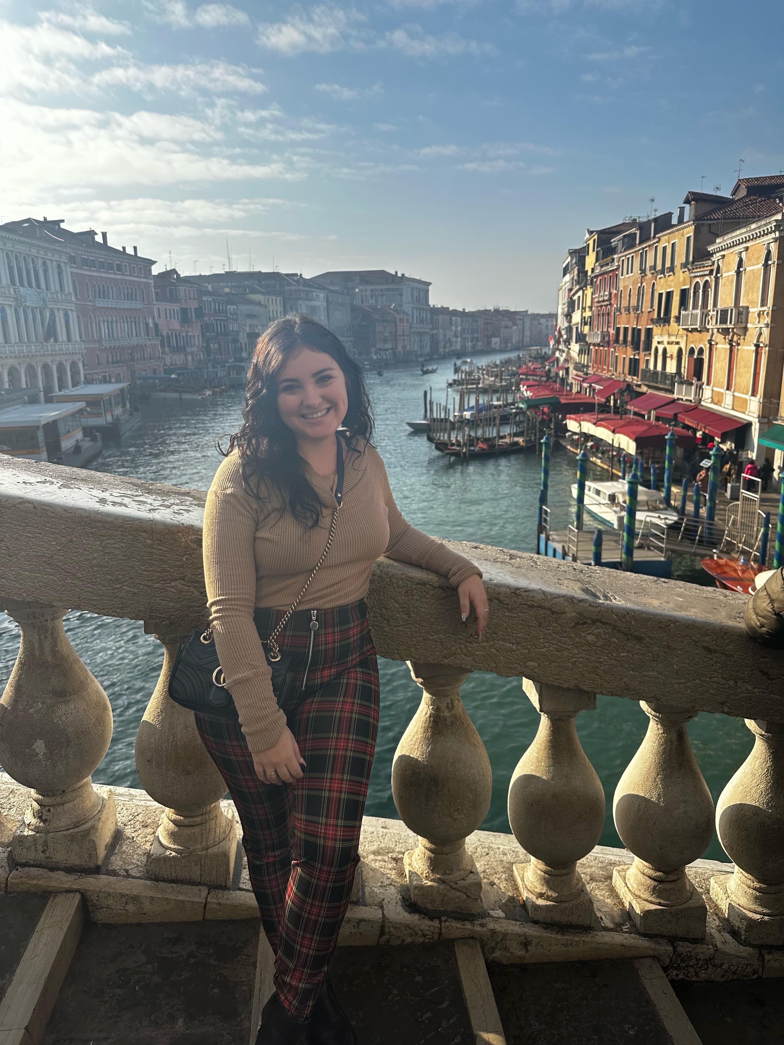 Picture of Brittany standing on stairs in Venice with the canal and yellow buildings in the background