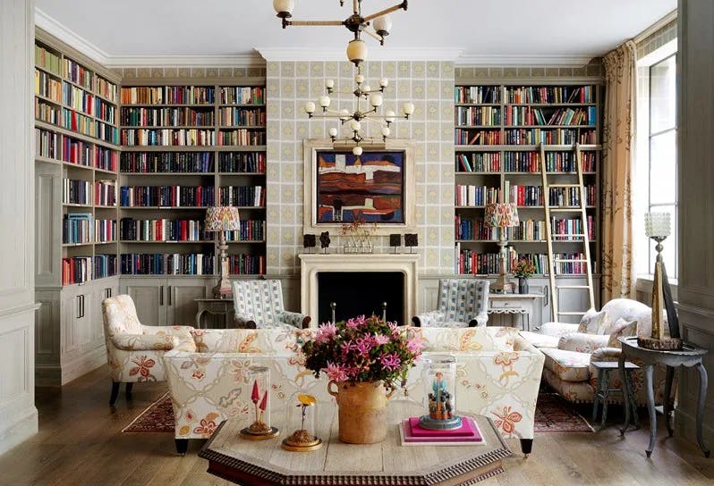 a handsome library with floor-to-ceiling bookshelves and fresh flowers