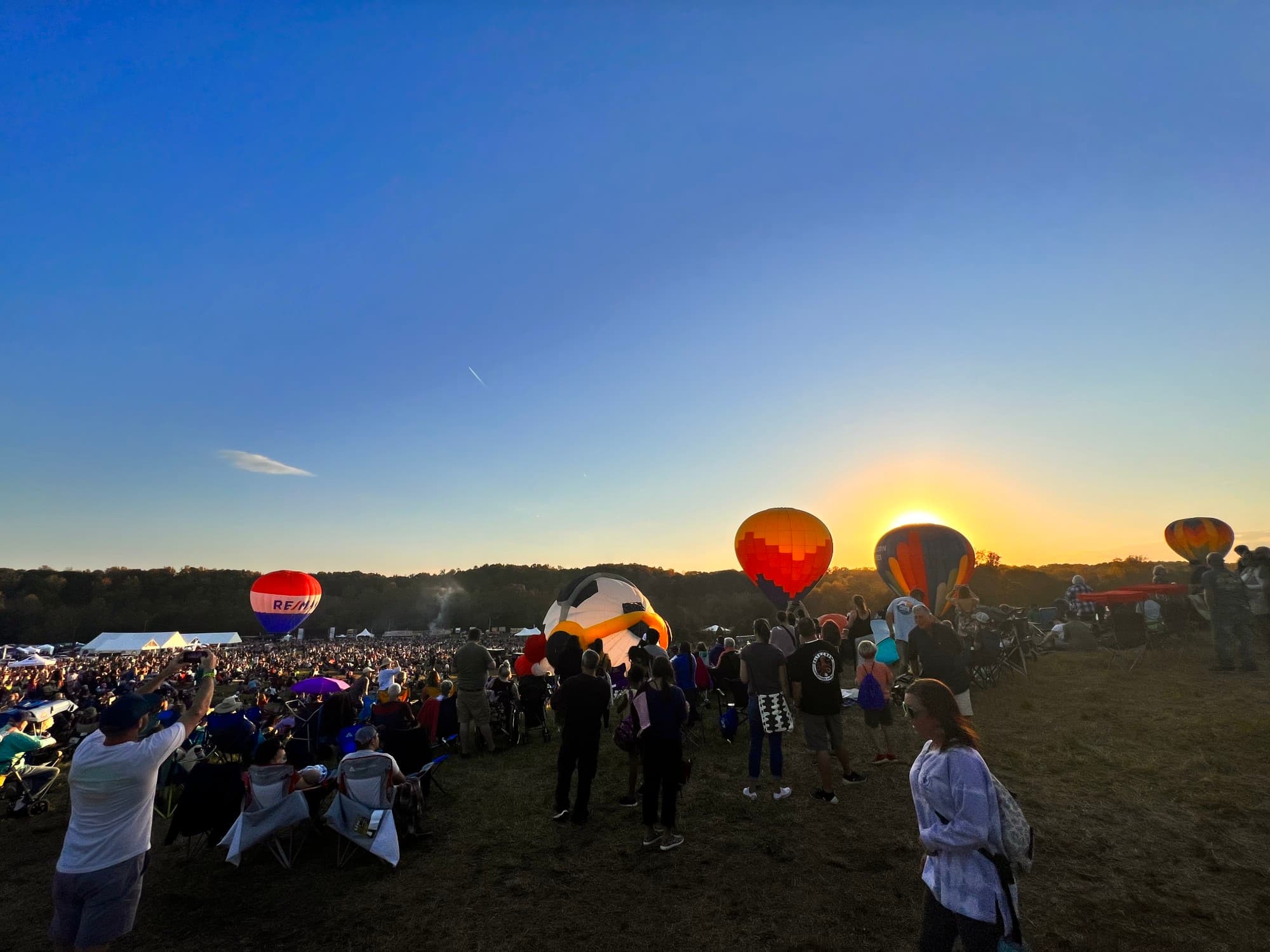 Hot air balloons on ground surrounded by people.