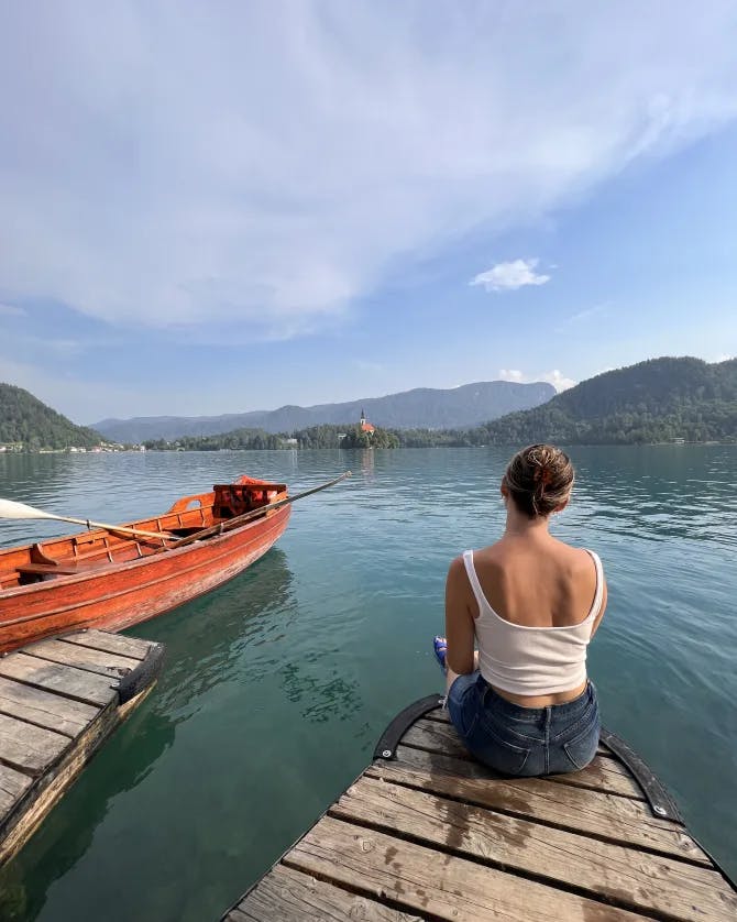 Picture of Courtney on a dock at Lake Bled with boats in the water. 