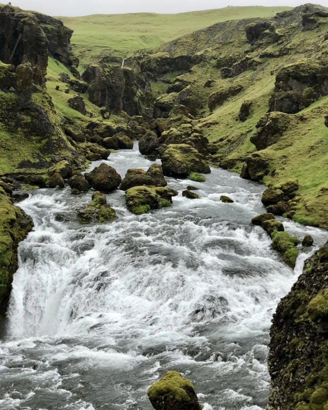 A beautiful picture of Skógafoss waterfall surrounded by mossy green plains