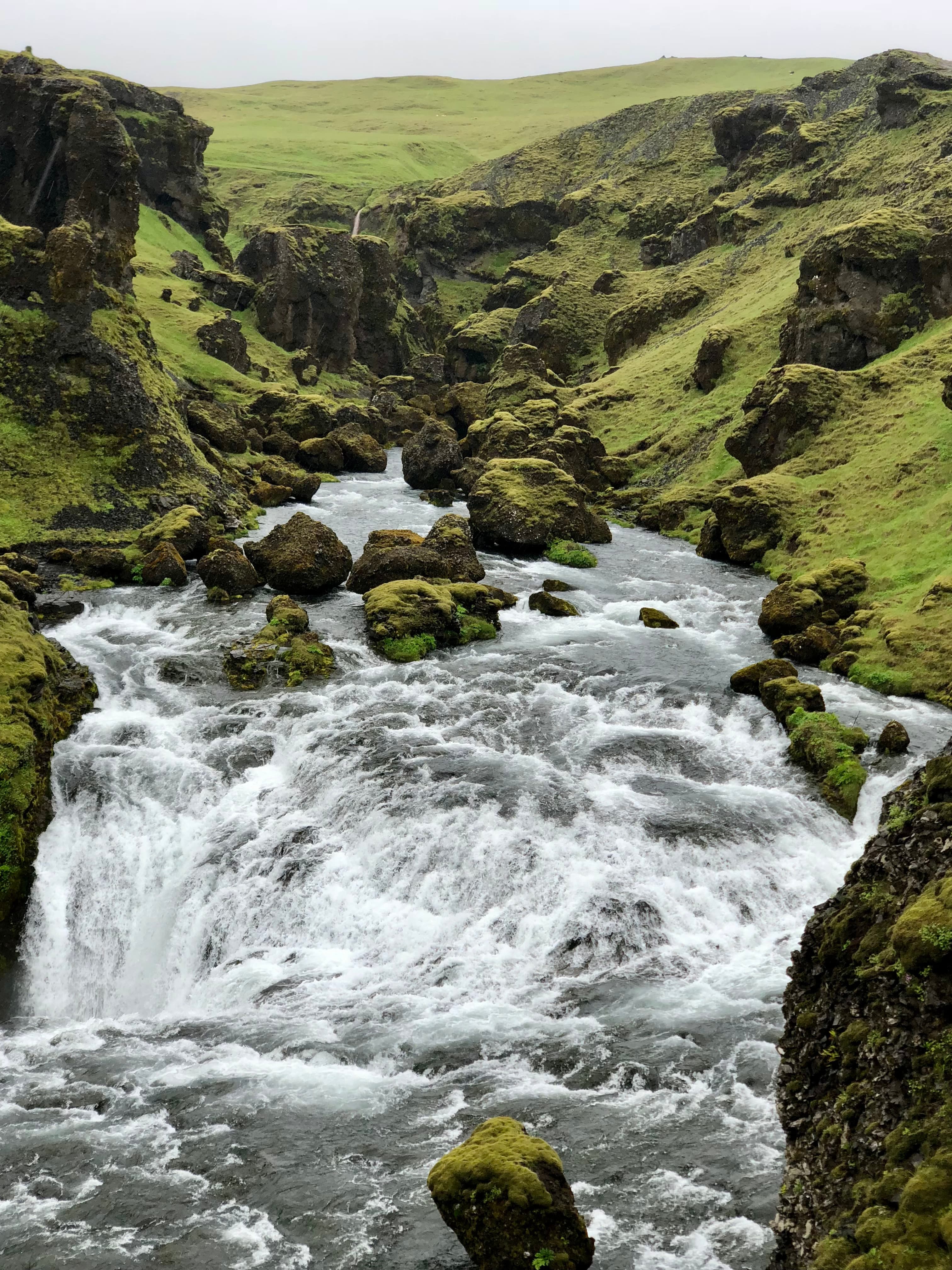A beautiful picture of Skógafoss waterfall surrounded by mossy green plains