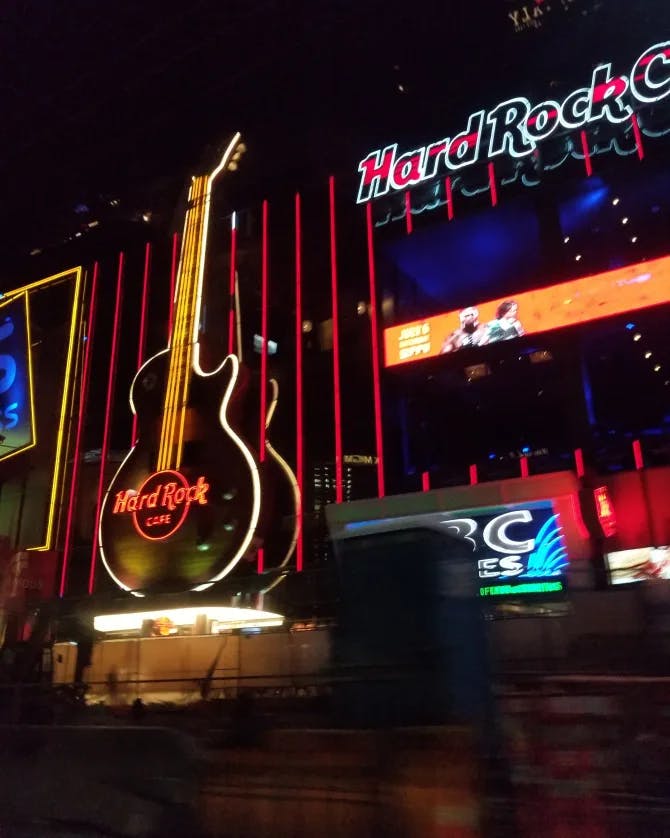 A view of the Hard Rock Cafe sign lit up at night. 