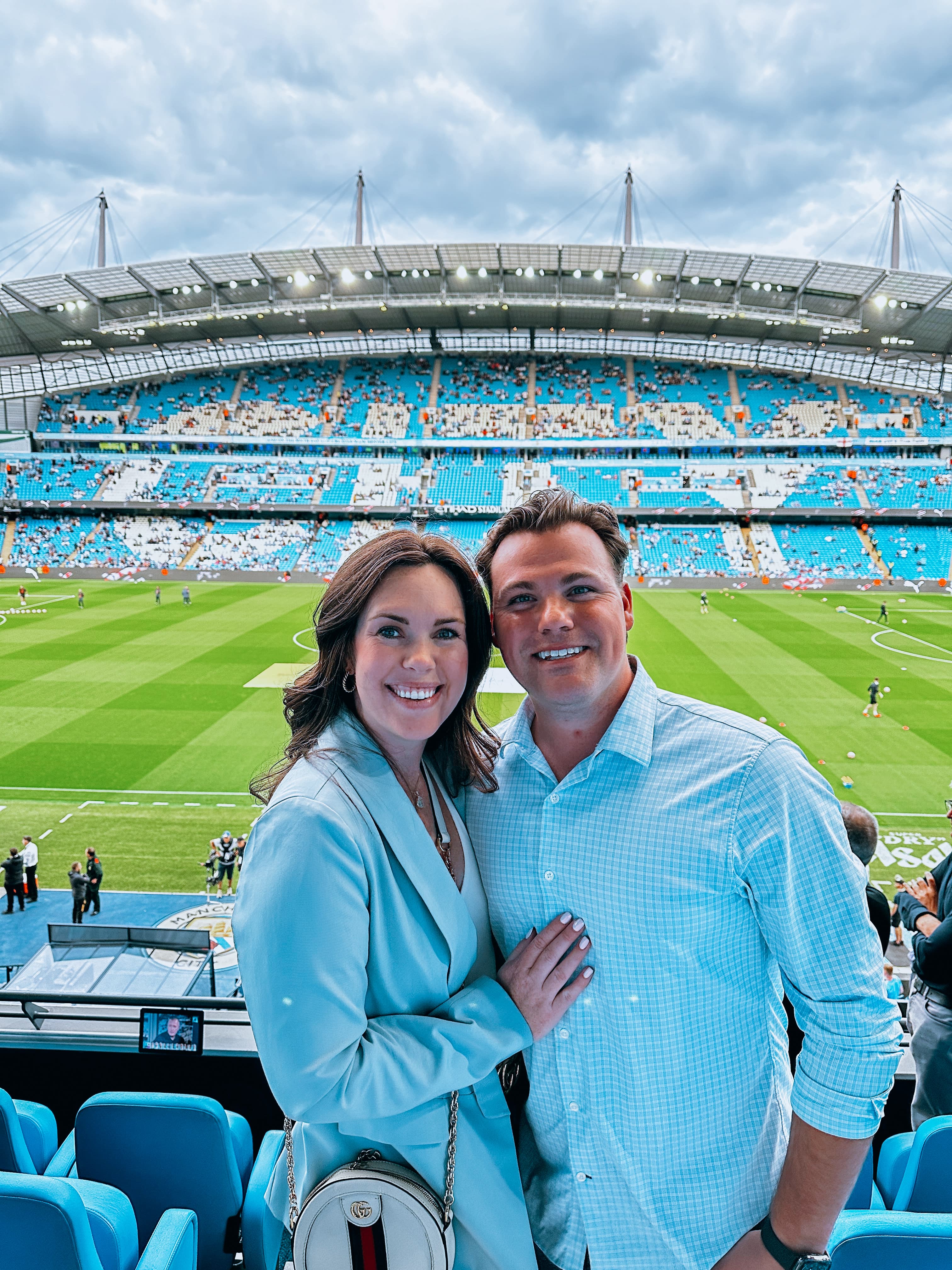 Travel advisor posing at a sports game with the event happening in the background.