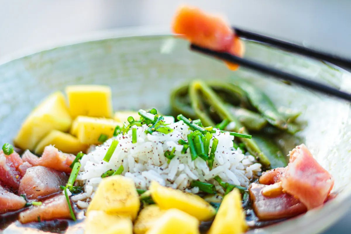 Close-up of a poke bowl with rice, fish and pineapple.