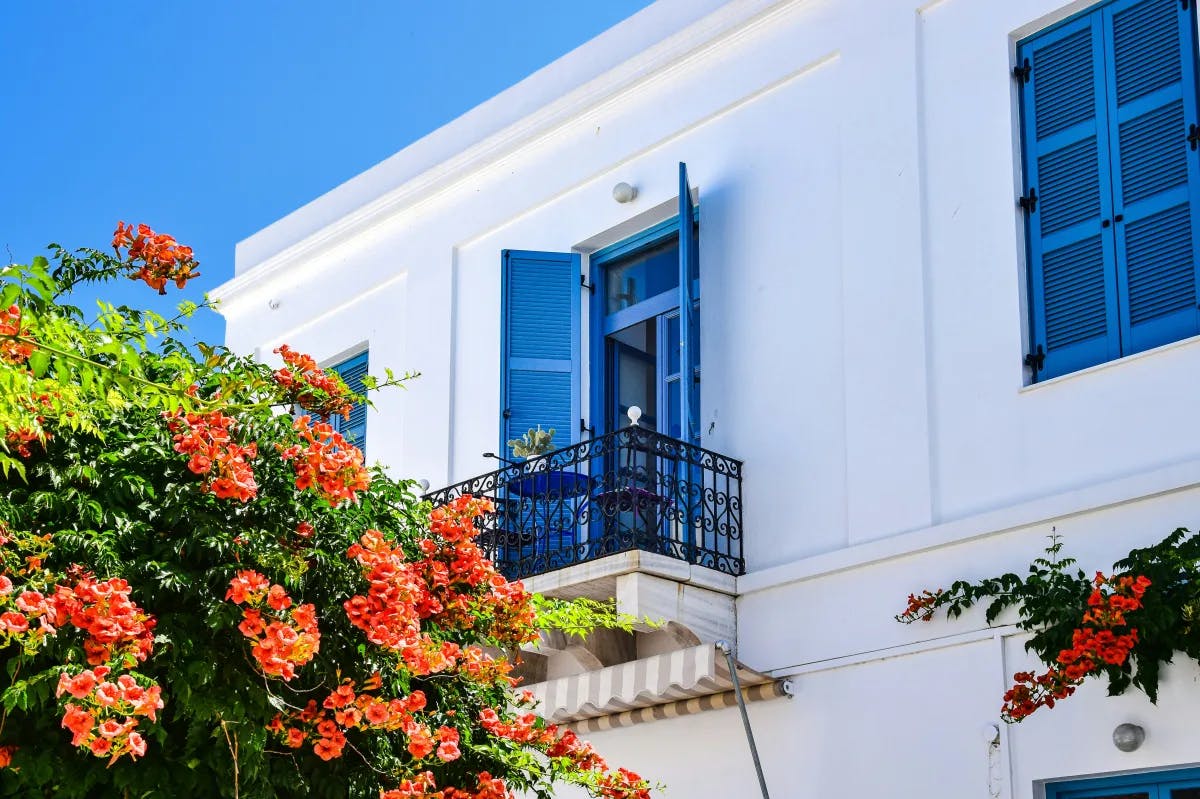 A picture of a white building with blue windows and flowers in front of it.