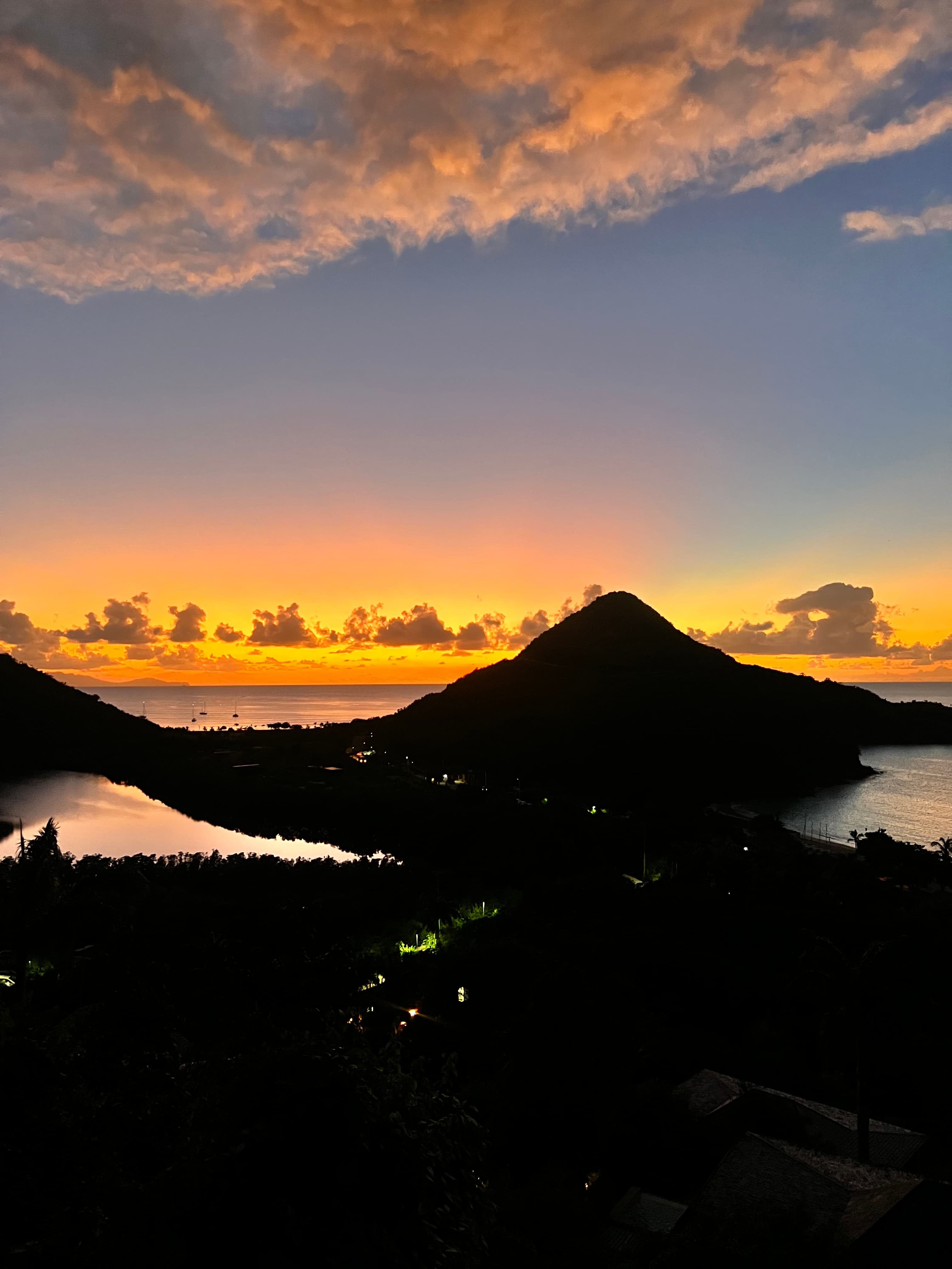 Sunset with golden and blue hues in a beautiful location. Mountains and clouds in the distance.