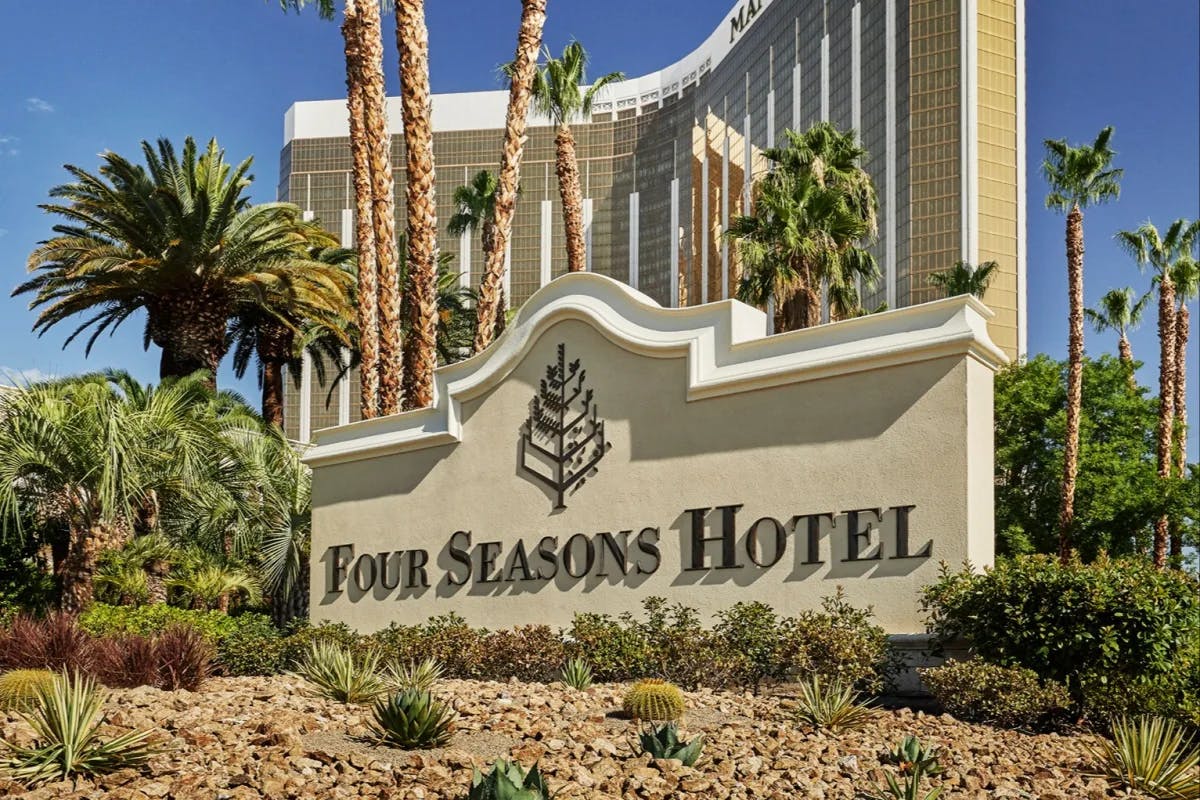 The exterior sign for Four Seasons Hotel Las Vegas standing amid desert vegetation at the resort ground's entrance, all within the shadow of Mandalay Bay