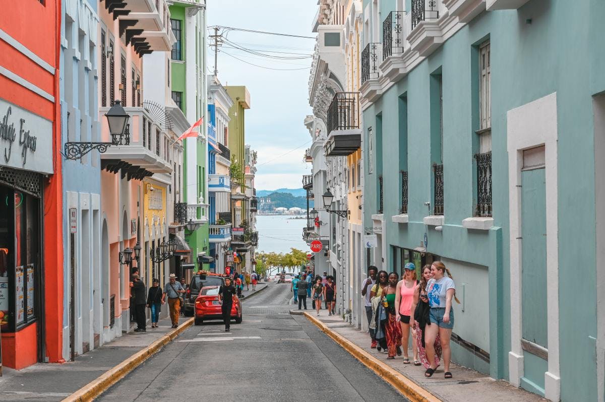 Narrow street with pastel-colored buildings leading to the beach in San Juan. 