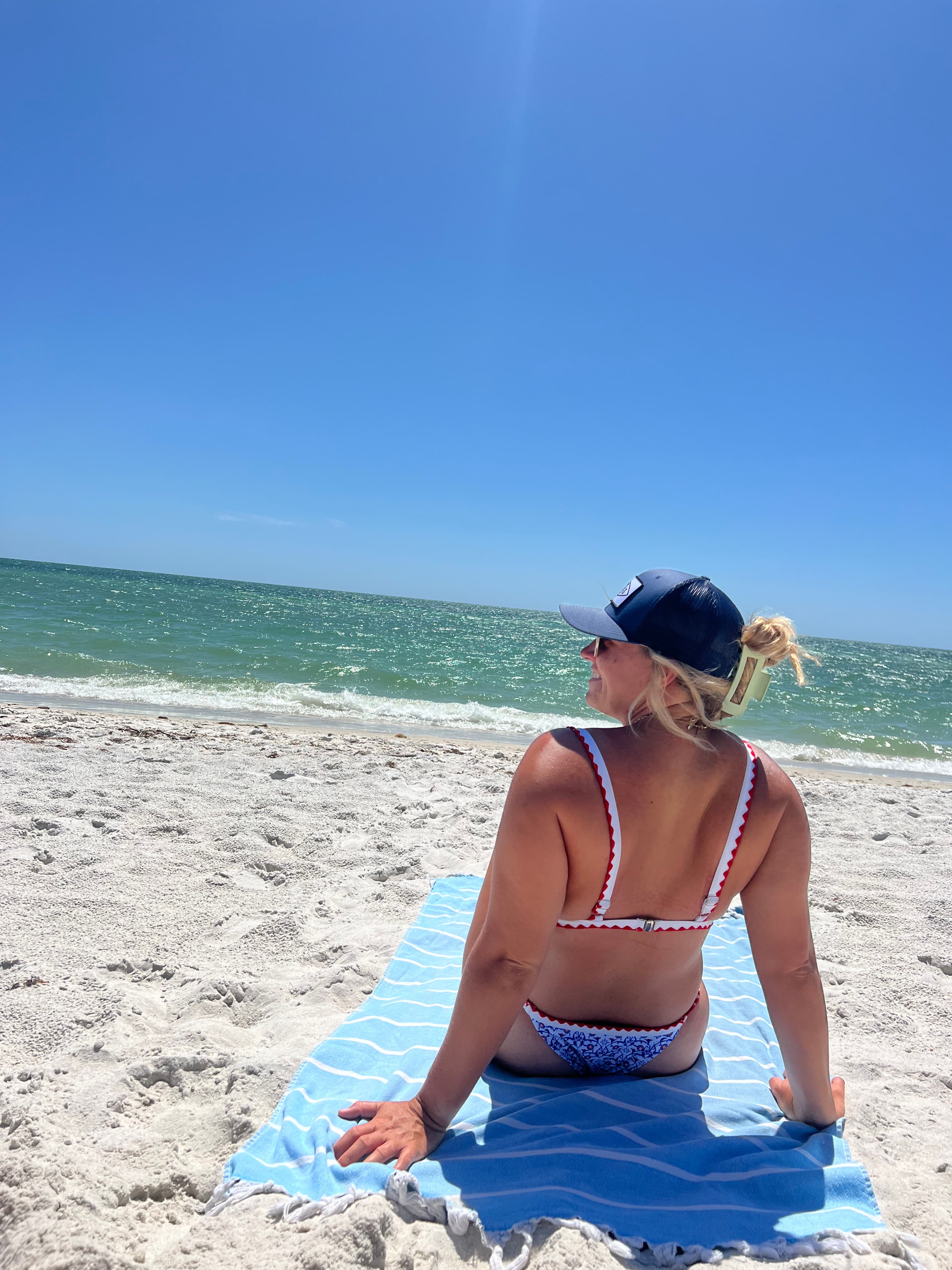 brittany sitting on a sandy beach with the coast line in the distance.