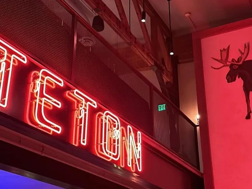 A picture of the interior of a restaurant with red neon sign.