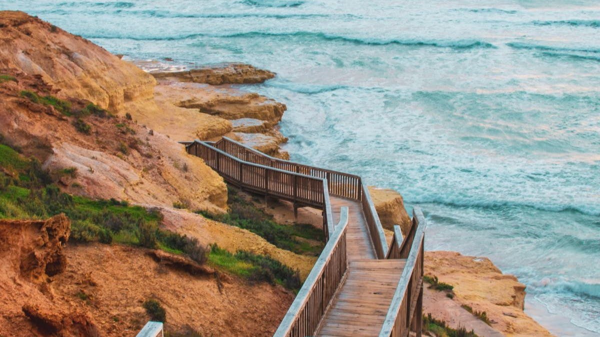 Brown, wooden stairs leading down to a beach 