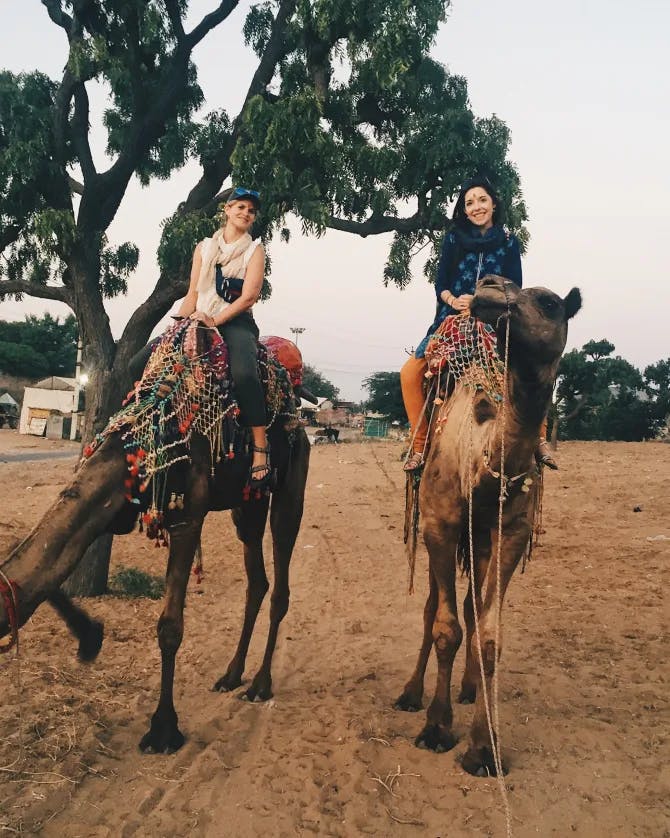 2 girls riding on camels