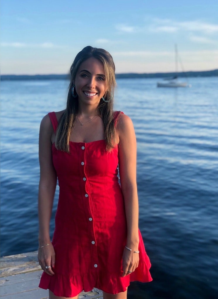 Travel advisor Cara Goodman wearing a red dress in front of a body of water