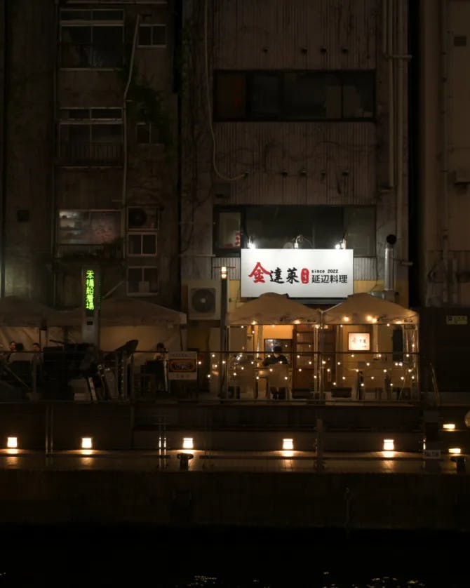 A view of a white restaurant at night with black and red lettering