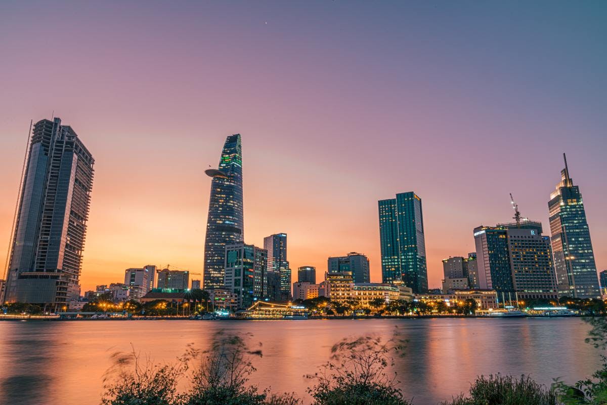 Skyline of Ho Chi Minh City in front of ocean during violet sunset.