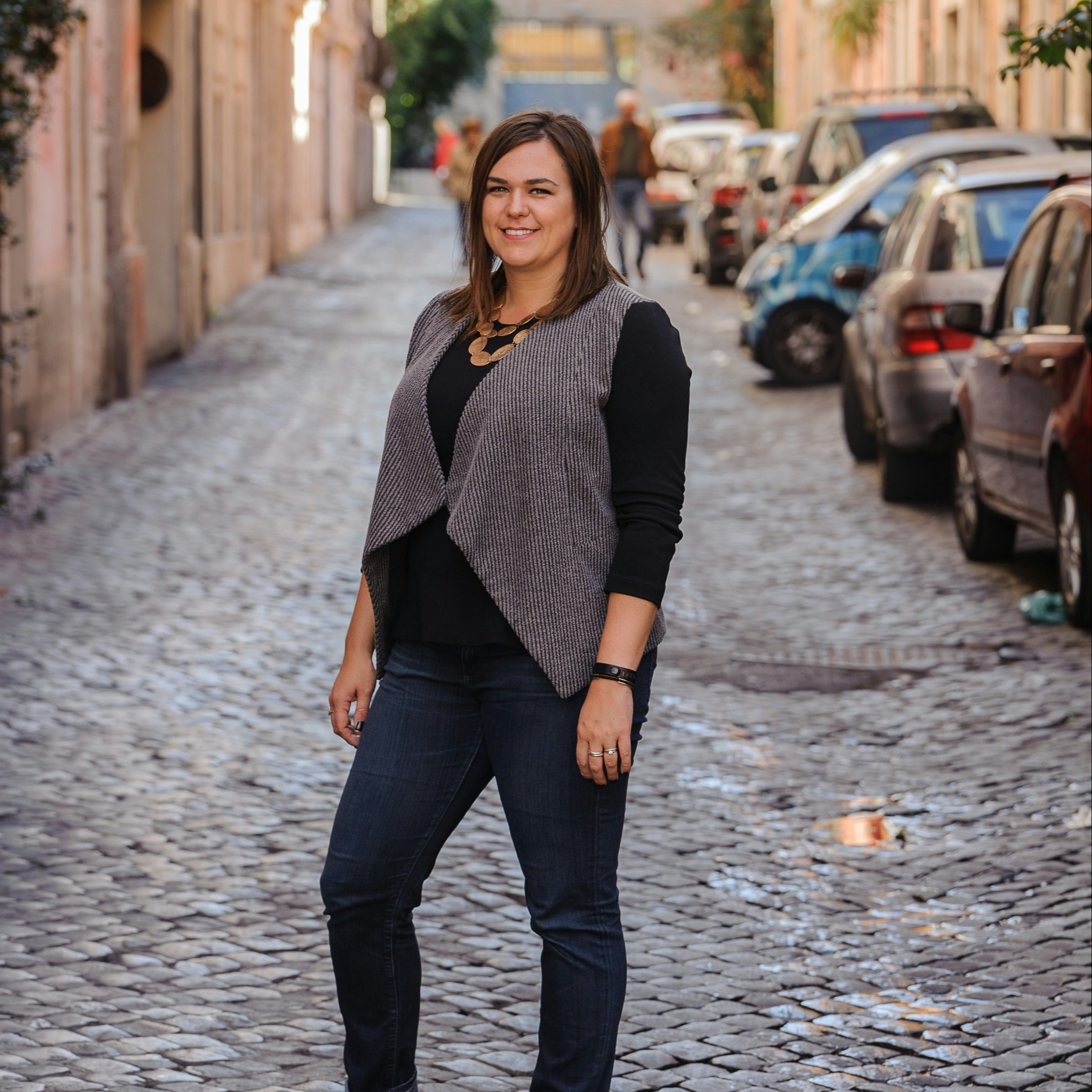 Travel Advisor Ashley Metesh standing on a European cobblestone street with cars in the background.