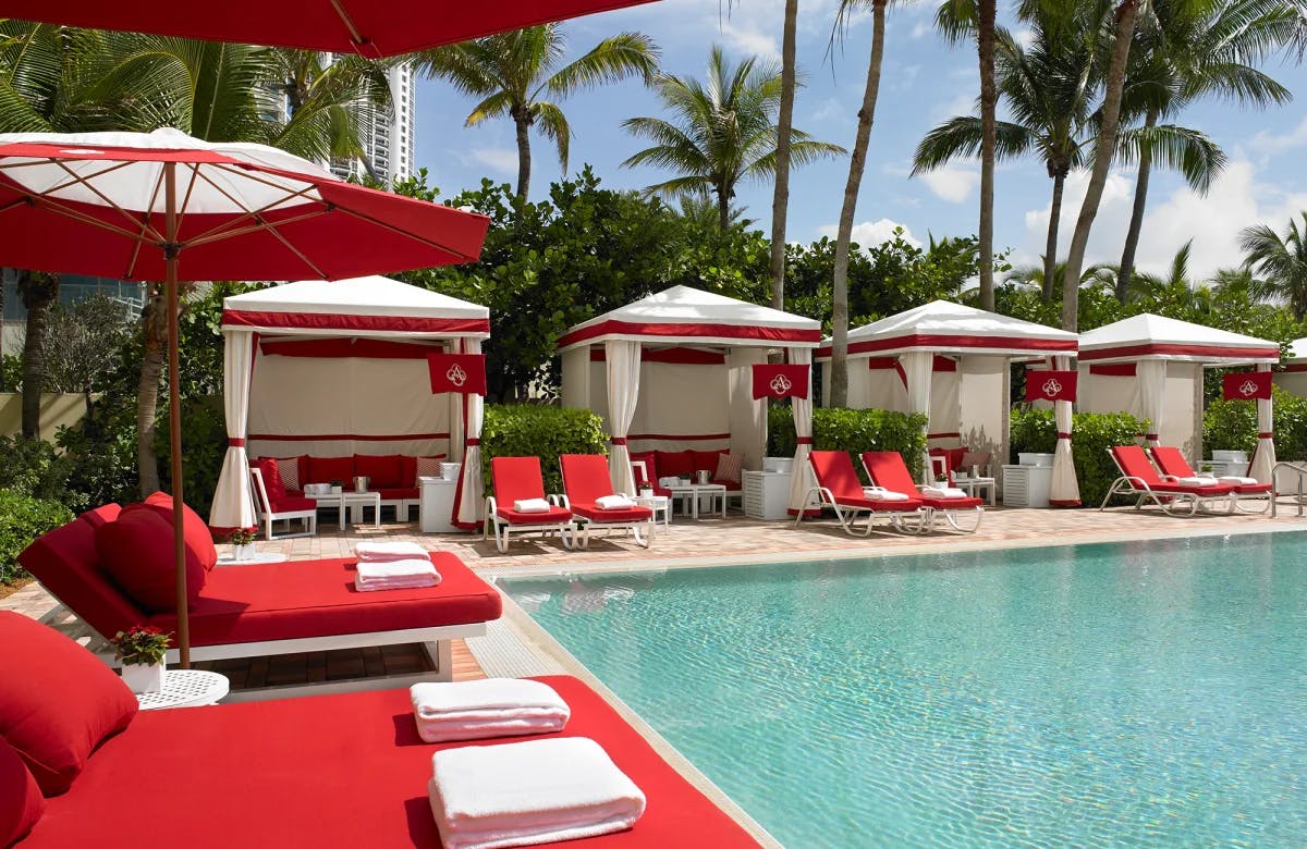 red chairs and cabanas surround a pool