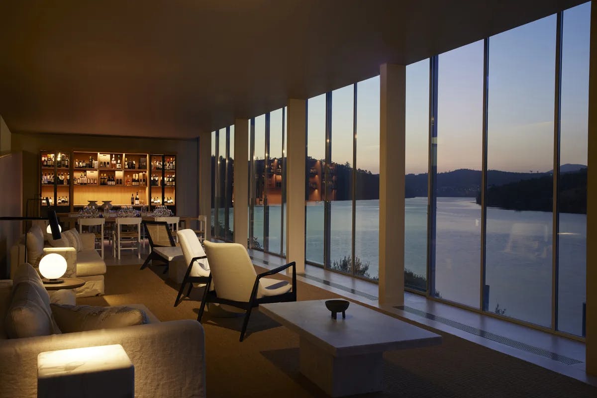 a cozy lounge with floor-to-ceiling windows overlooking a body of water