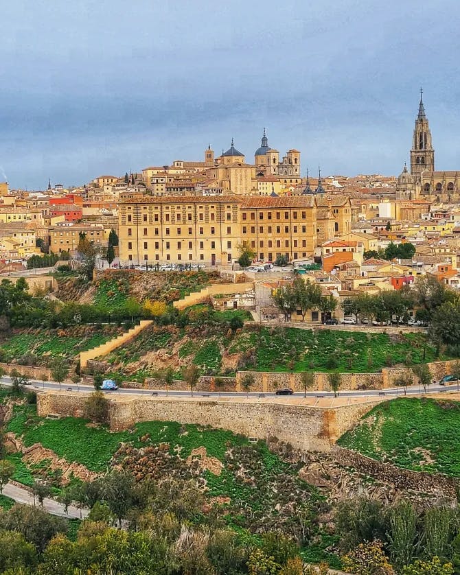 An aerial view of tan buildings, pathways, grass and trees in Toledo, Spain