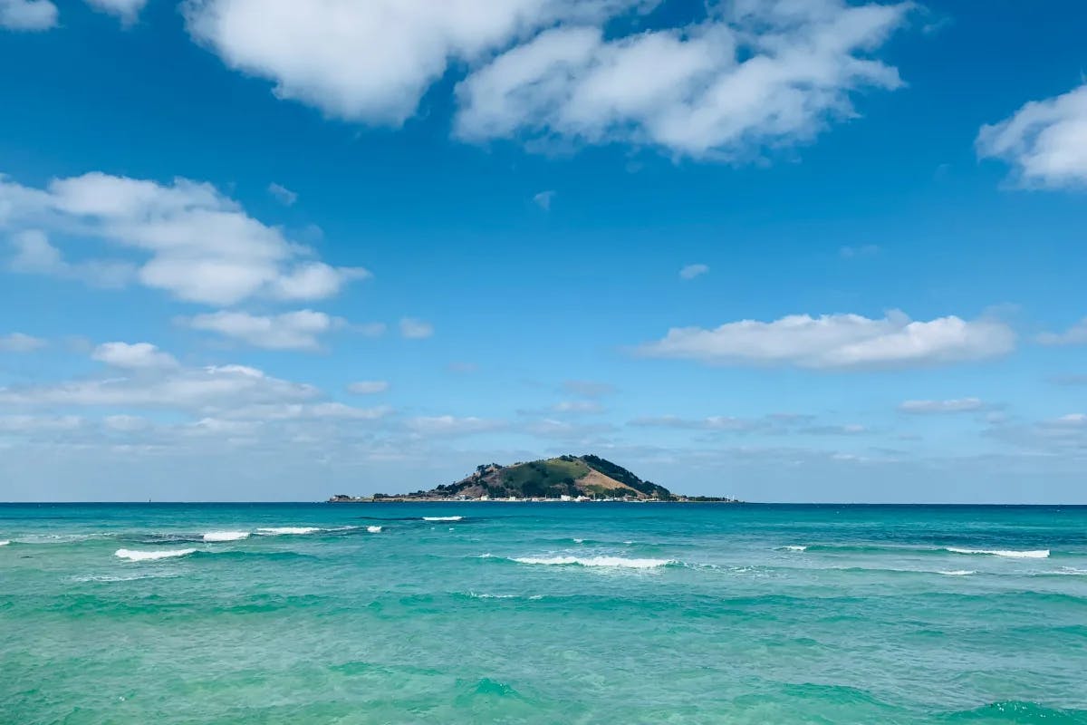 A picture of an Island under the blue sky with white clouds.