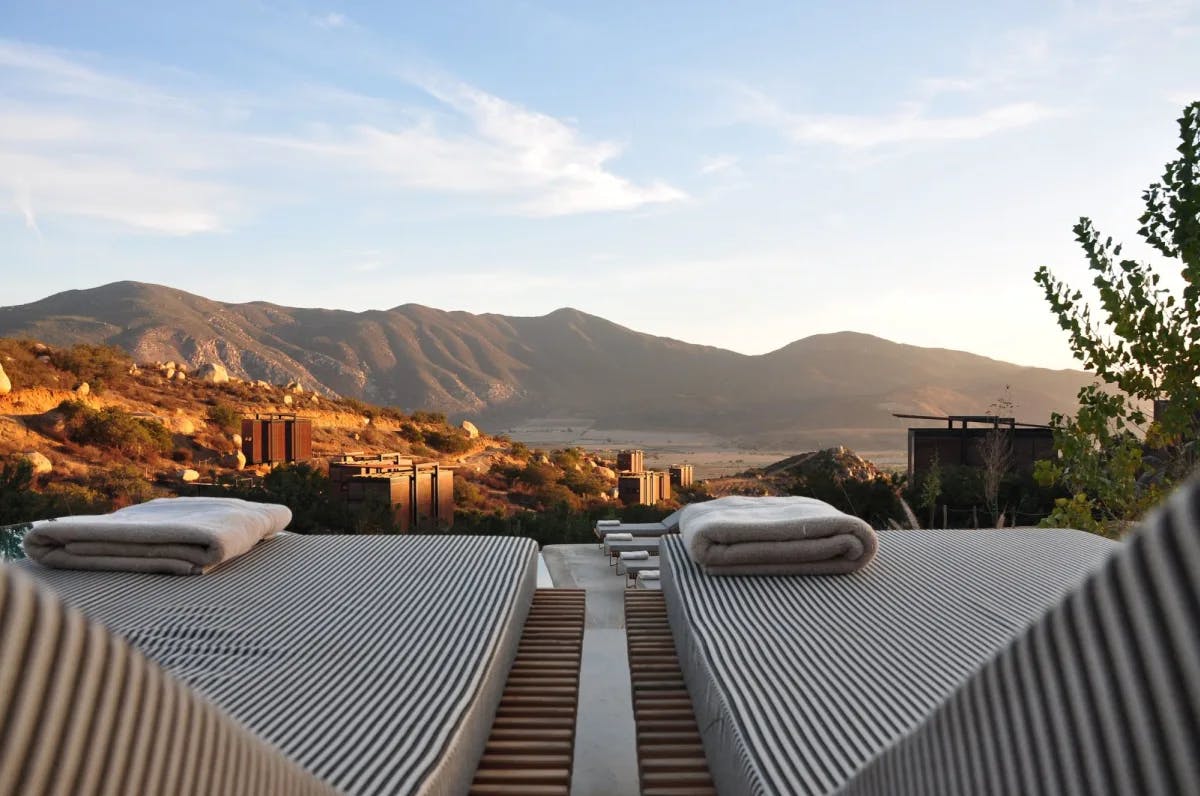 Plush sun loungers with folded towels on a rooftop hotel with scenic mountains in the distance