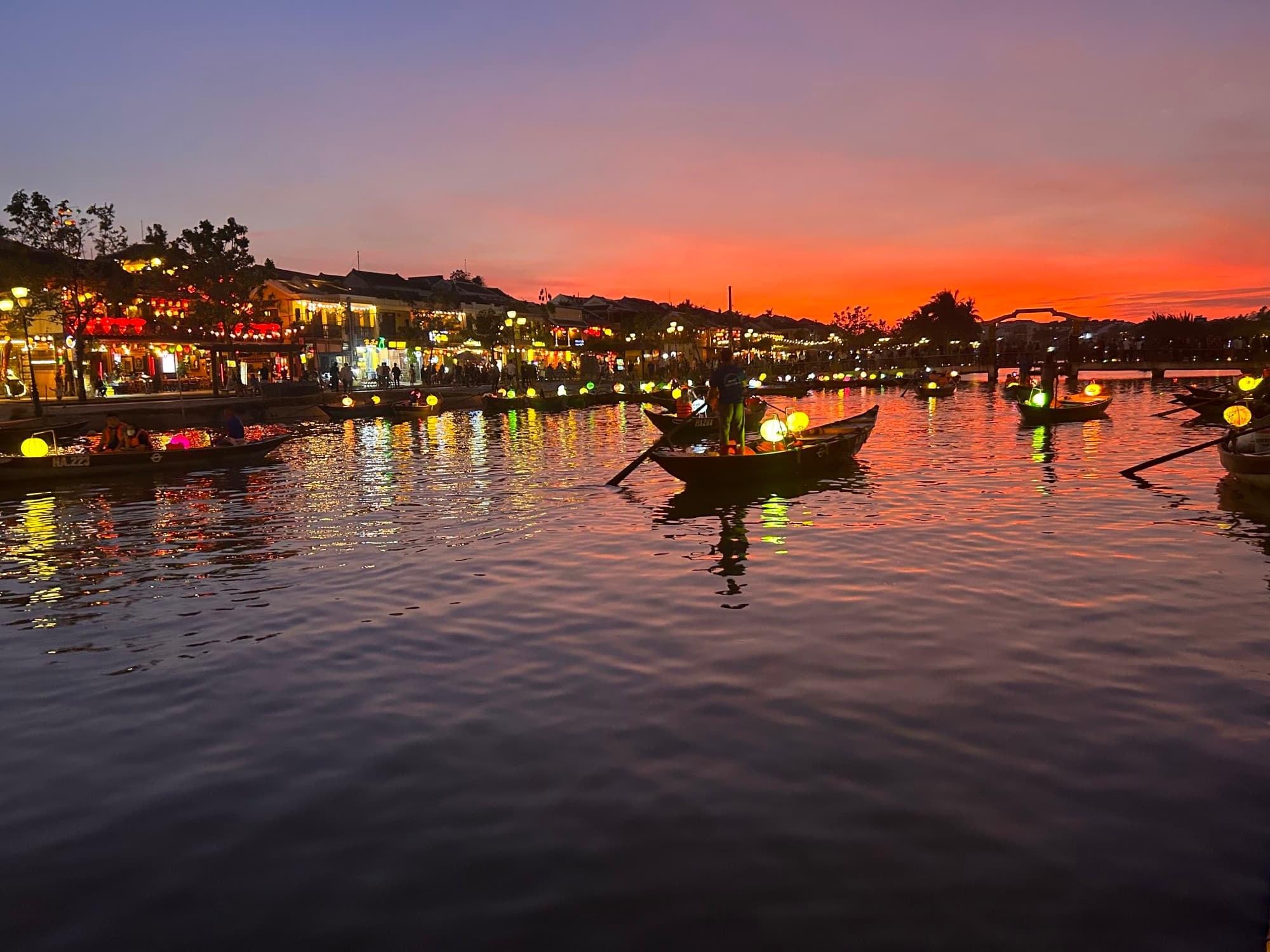 Canoes float on a river at dusk.