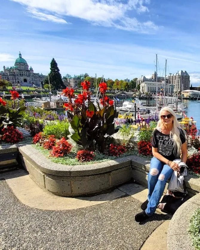 Travel Advisor Posing near a water way with a beautiful flower bed.