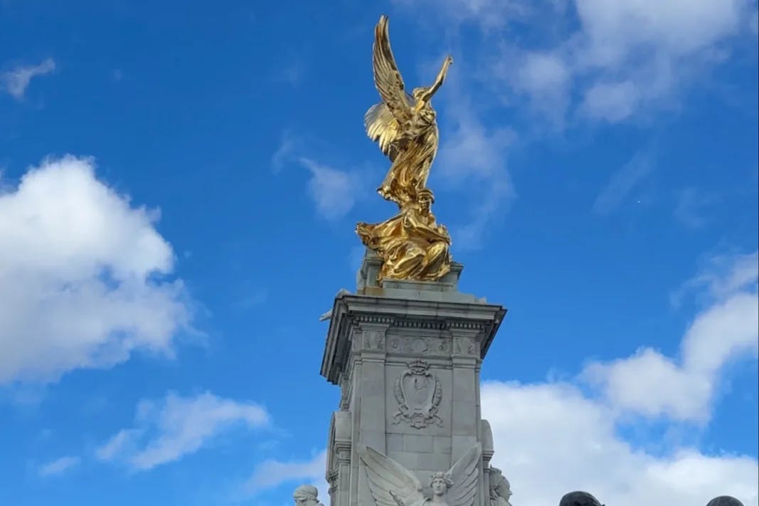 A gold statue on top of a monument during the daytime