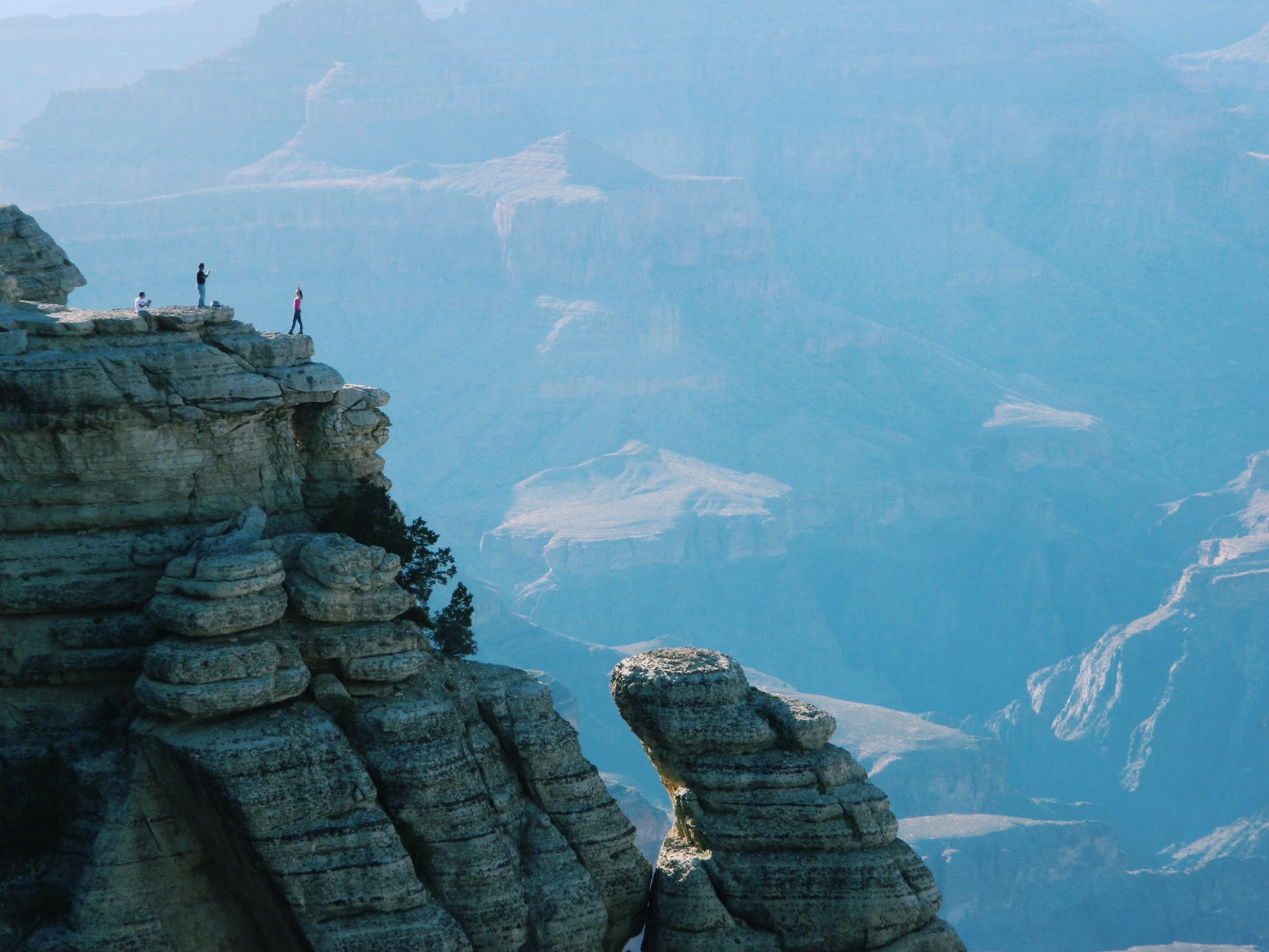 A large rock formation with a cliff edge and people taking in the view of the valley.