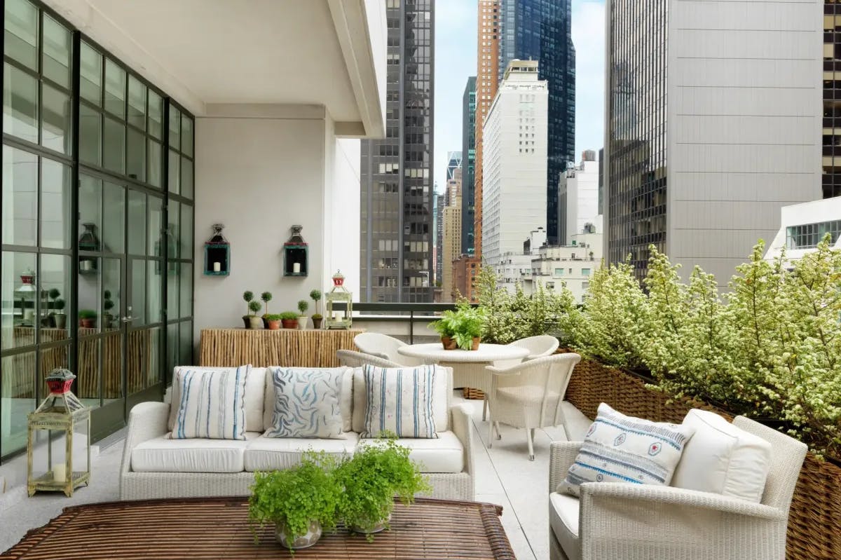 an urban terrace with cozy white couches and green plants