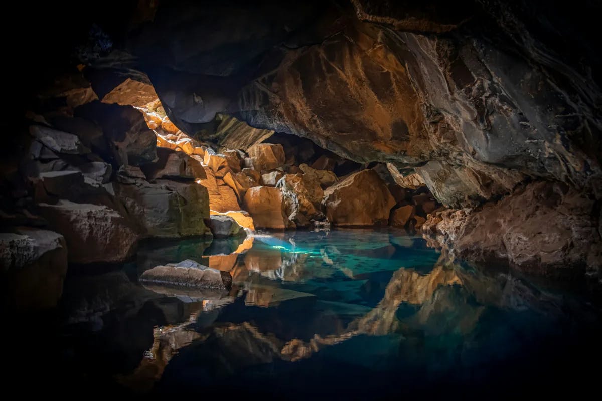 A picture of a cave filled with blue-colored water with sunlight coming through the cracks