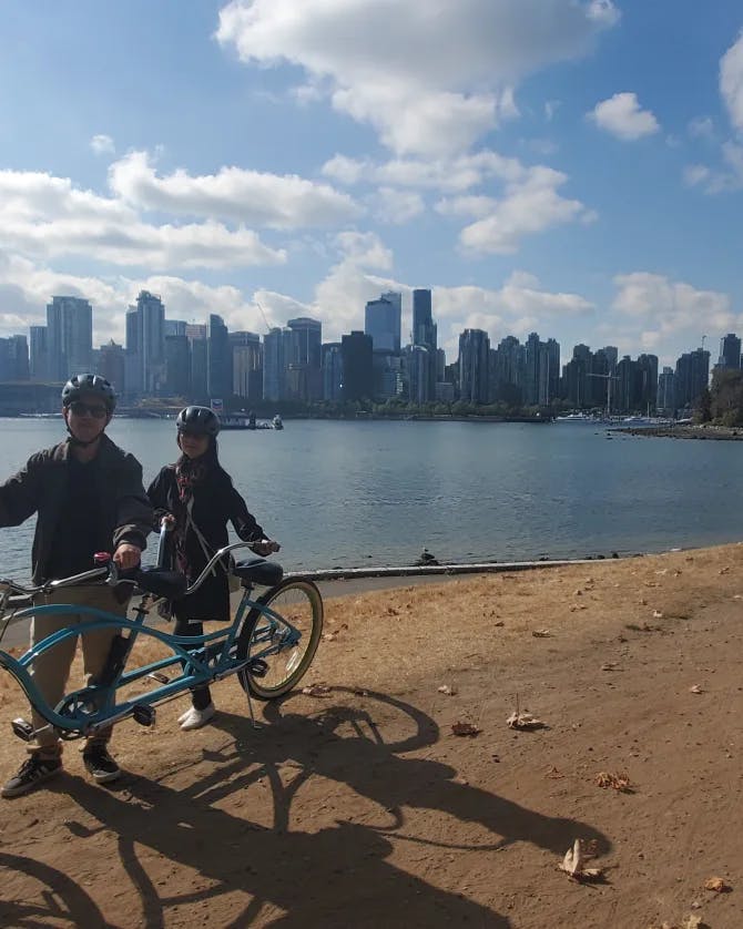 Aron cycling along a sandy coast with a city skyline in the background.