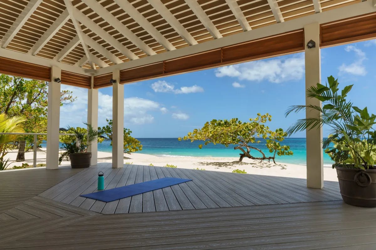 beachside pavilion with a blue yoga mat overlooking a turquoise sea