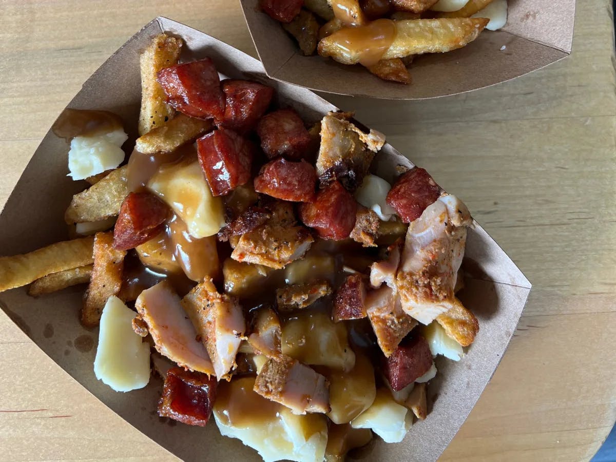 A tray of poutine on a wooden table.