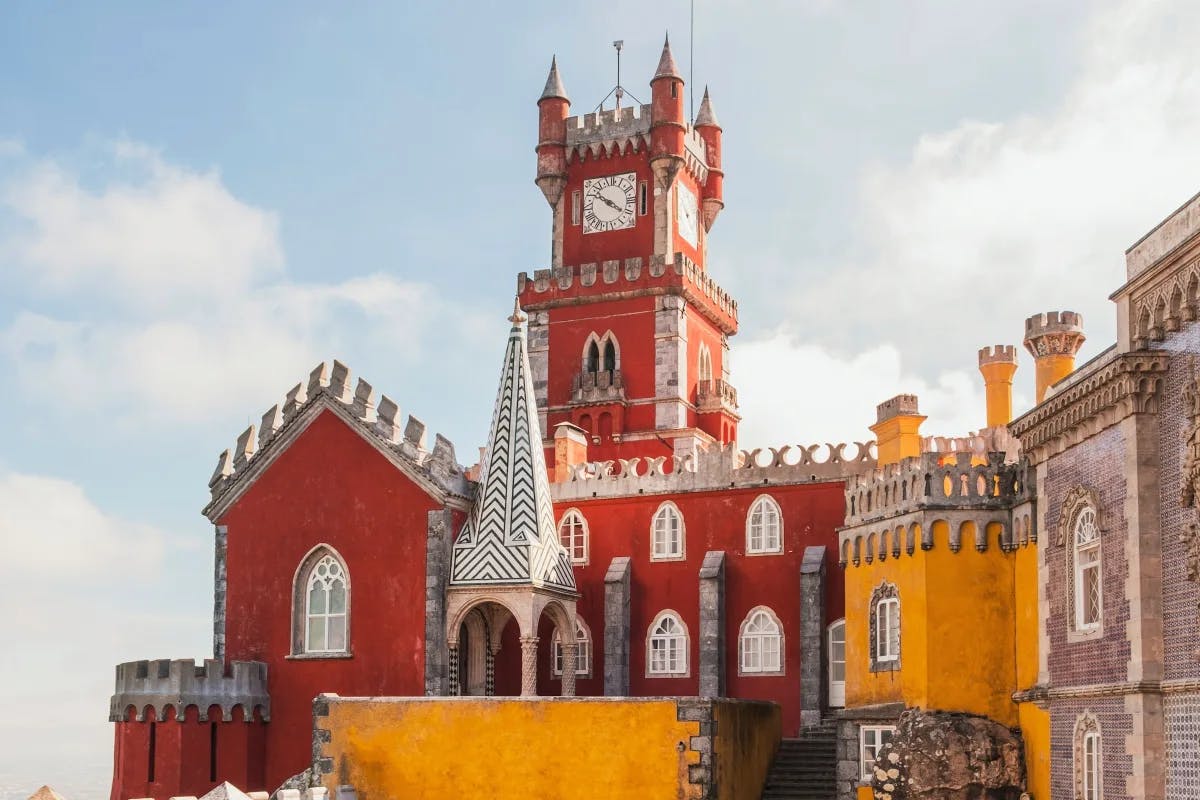 The unique architecture style of Pena Palace is on full display, with a castle turret standing imposingly above red and yellow stone walls and features