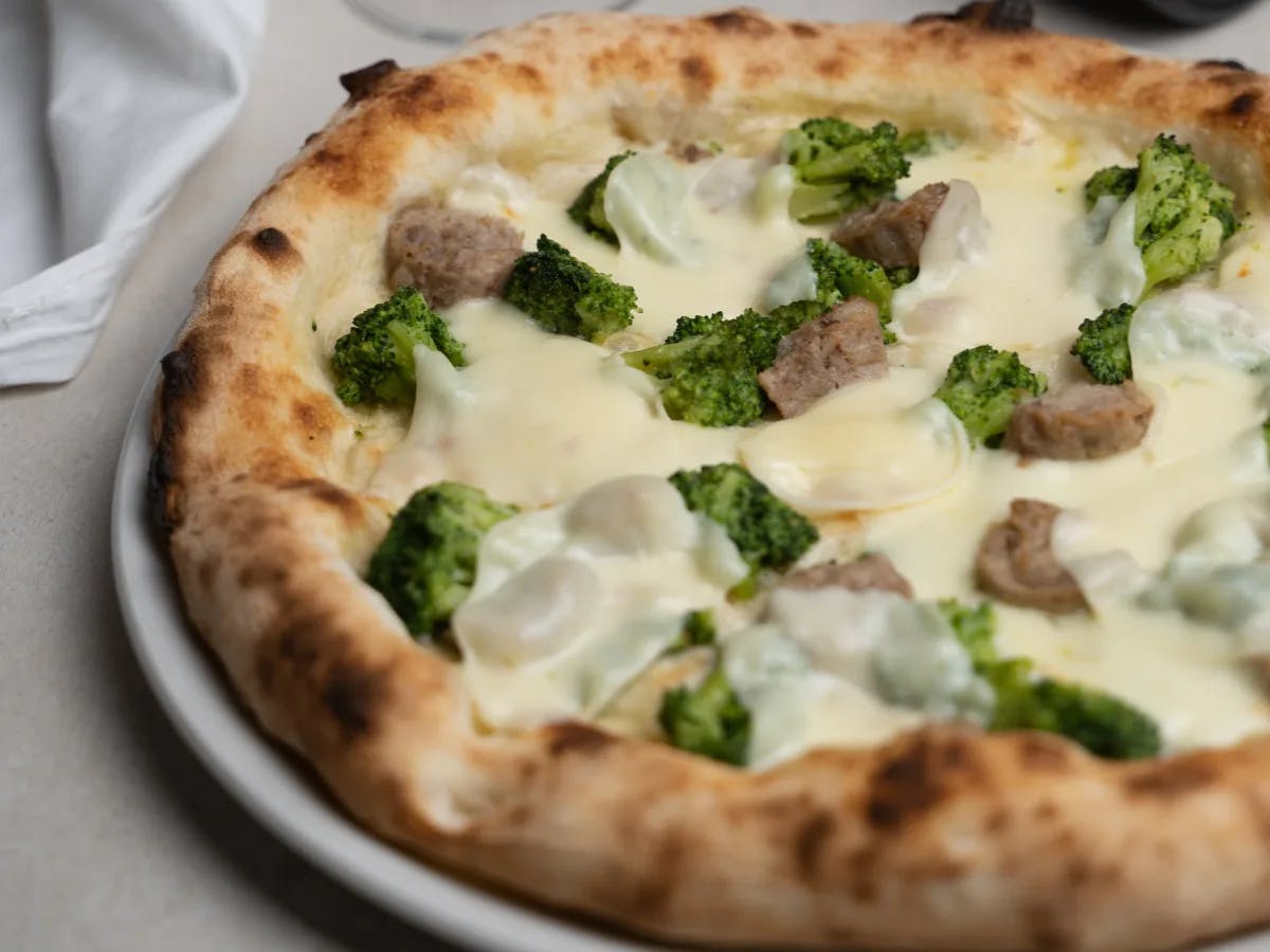 A pizza with broccoli and meat  as a topping.