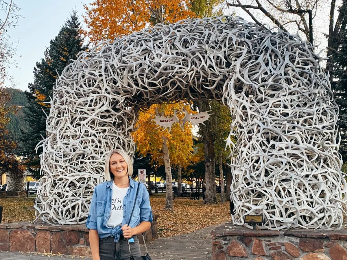 A woman in front of an antler arch.
