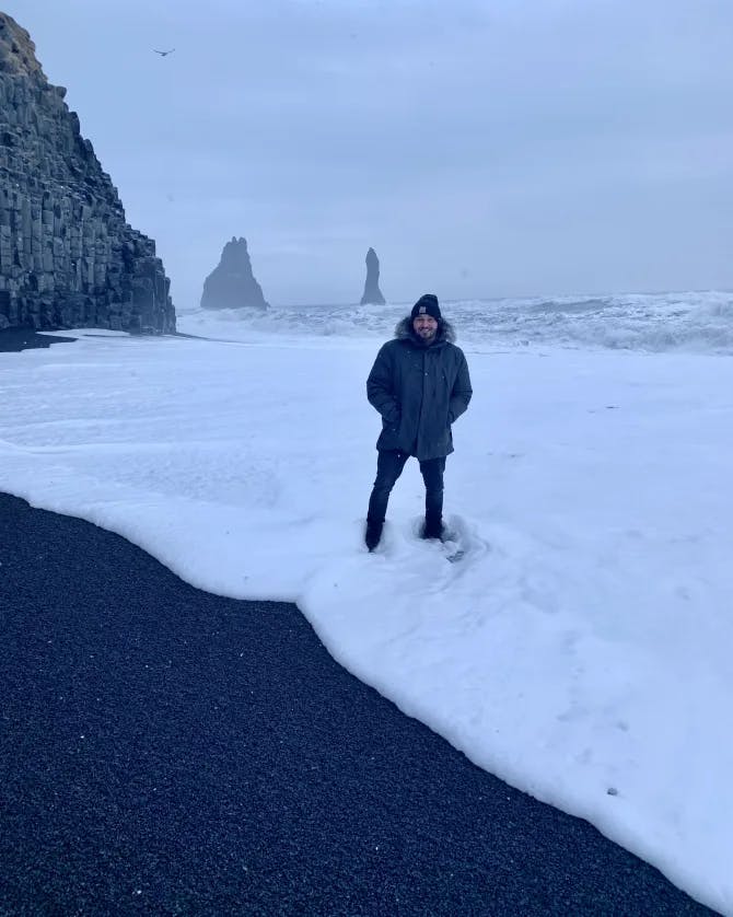 John standing in the snow with large rock formations in the background on a cloudy day