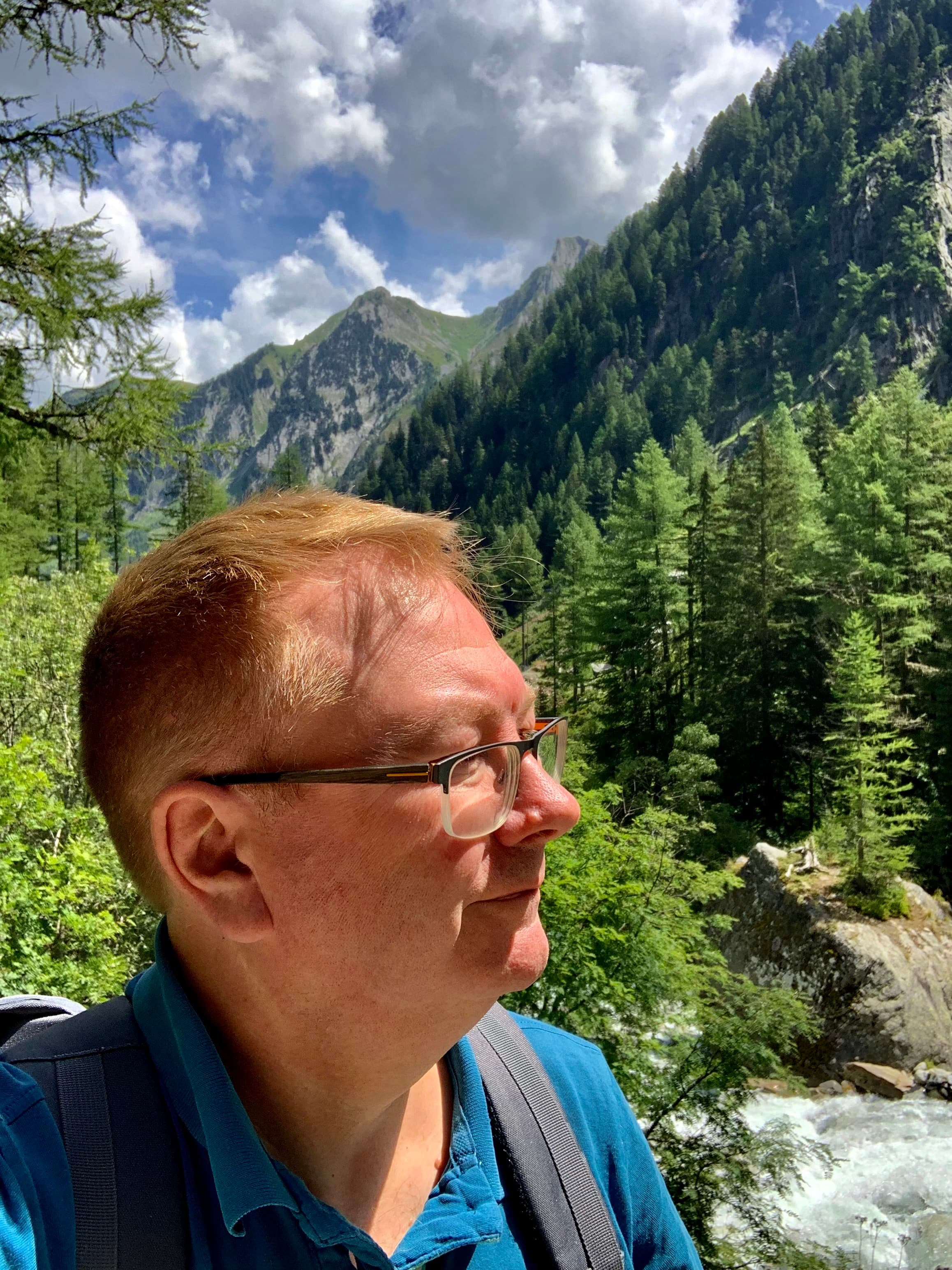 A profile view of Pat amongst the pine trees and mountains.