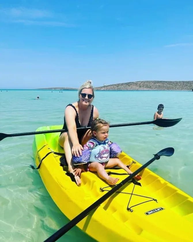 Picture of Nicole with a child on a yellow kayak in the ocean. 