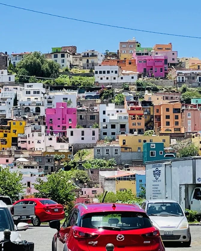 Cars on a road in front of a colorful city landscape on a sunny day