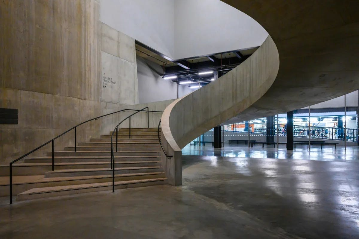 A curved gray concrete staircase in a modern building lobby